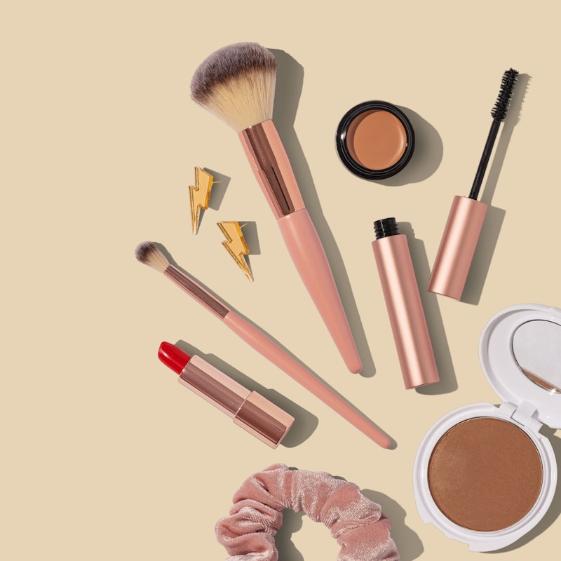 Pinceau, mascara, rouge à lèvres et poudre bronzante